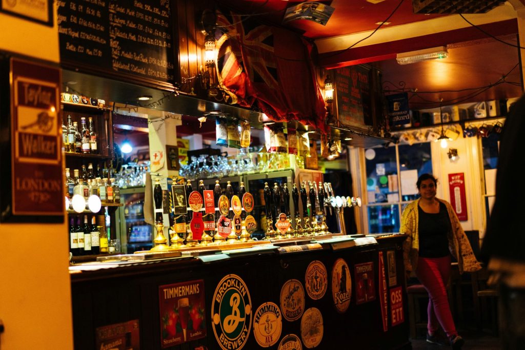 A busy bar with many taps and bottles