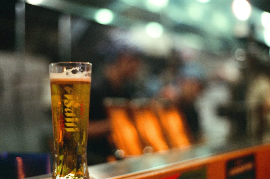 A glass of beer sits on a bar.