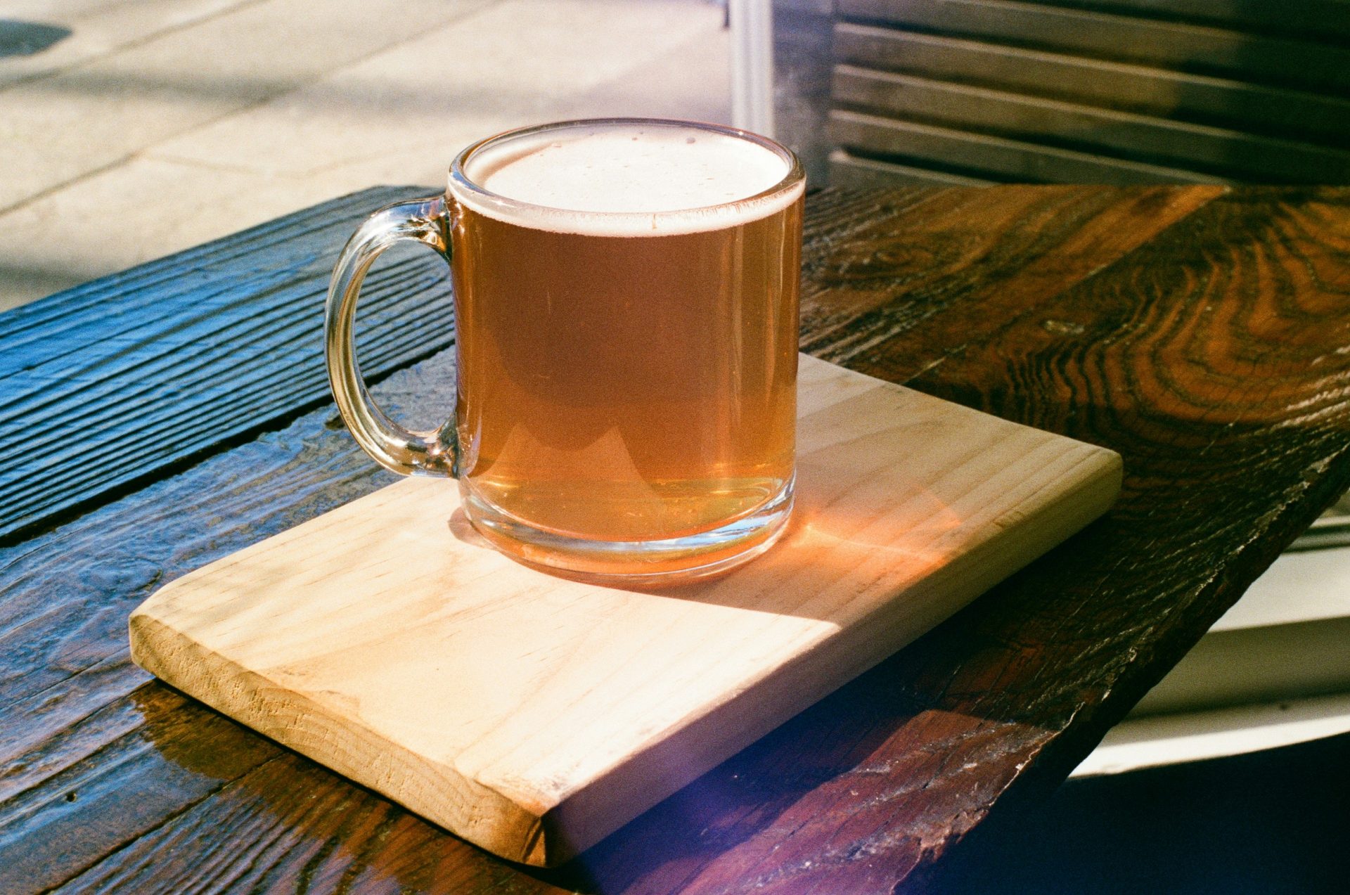 a glass of beer sitting on top of a wooden table